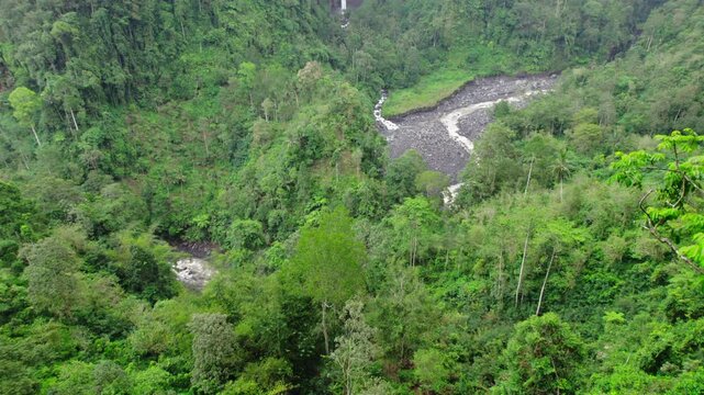 High angle drone aerial view of Biru waterfall and jungle in East Java, Indonesia