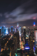 Obraz premium Rooftop view of Midtown, Manhattan with the Empire State Building and H&M building during the night with beautiful clouds and the city lit up with beautiful lights from the Midtown buildings. 