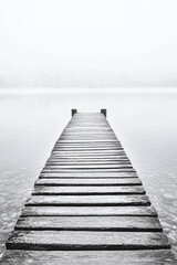 Obraz premium Tranquil Wooden Pier on a Misty Lake