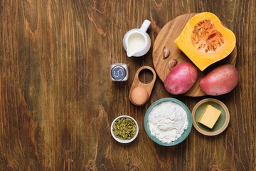 Prepared ingredients for pumpkin gnocchi or dumplings on brown wooden background. Recipes pumpkin.
