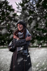 Fototapeta premium Happy woman standing outside in the park in the snowfall