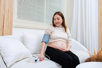 Pregnant woman measures blood pressure with sphygmomanometer equipment.