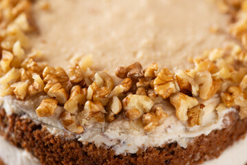 Pumpkin layered cake with vegan coconut and caramel cream decorated with walnut. Homemade cake, sugar, gluten and lactose free. Close up.