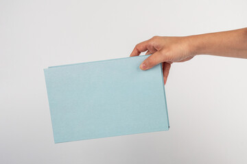 Blank book cover in hand on white background.