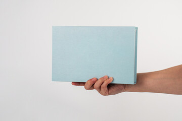 Blank book cover in hand on white background.