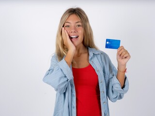 Astonished positive Beautiful teen girl wearing denim jacket arm face hold bank plastic card...