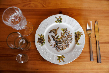 Elegance Unserved: An Artful Arrangement of a Decorated Plate, Crystal Glasses, and Cutlery on Rustic Wood.