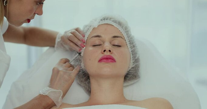 Beautician doctor makes injections into the skin of the face of a young beautiful woman. Top view close-up shot of platelet rich plasma face injections procedure.