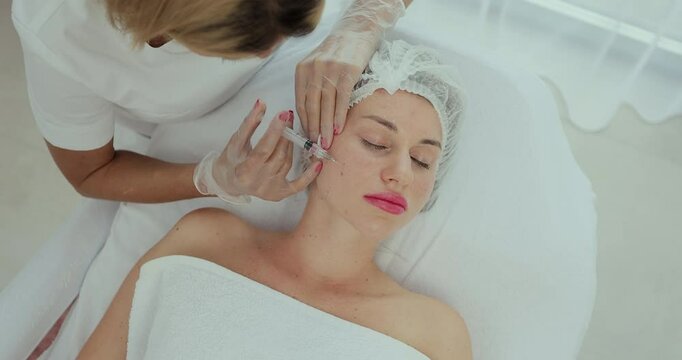 Beautician doctor makes injections into the skin of the face of a young beautiful woman. Face mesotherapy procedure in a beauty salon. Mesotherapy, biorevitalization. Cosmetology.