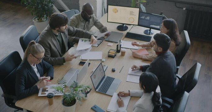 Team leader talking to diverse group of people employees giving documents leading meeting in office. Professional cooperation and businesspeople concept.