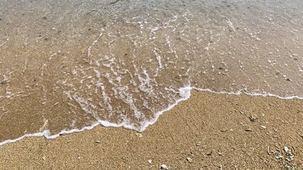 Small waves on a beach, Tiny waves lapped at the shore. Gentle ripples danced across the calm, shallow water. Kondang Merak Beach in Malang Indonesia