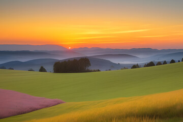 Obraz premium A vibrant sunset paints the sky with hues of orange, yellow, and pink, casting a warm glow over rolling hills and a lush, green meadow. The sun dips below the horizon, leaving a trail of light across 