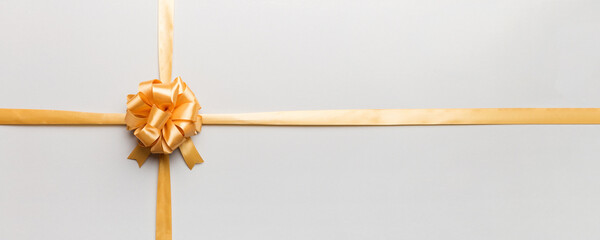 Top view of gold ribbon rolled and yellow bow isolated on colored background. Flat lay with copy...