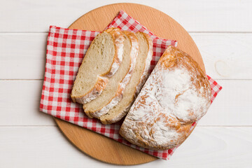 Freshly baked bread slices on cutting board against white wooden background. top view Sliced bread