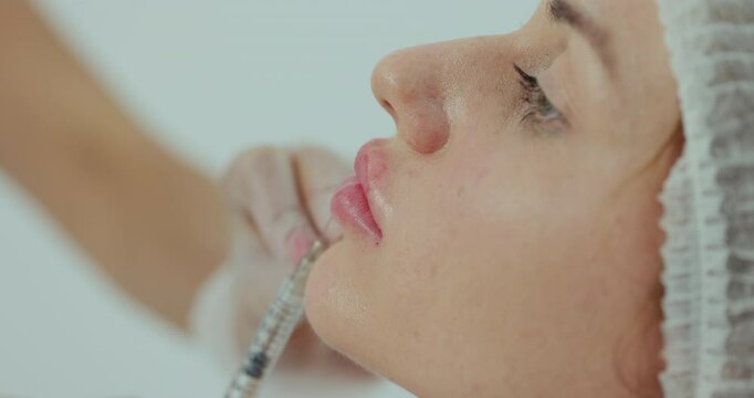 Close up of female lips having hyaluronic acid lifting by syringe. The process of lip augmentation in a young beautiful woman. Beauty concept.