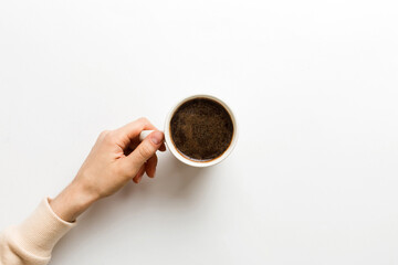 Minimalistic style woman hand holding a cup of coffee on Colored background. Flat lay, top view cappuccino cup. Empty place for text, copy space. Coffee addiction. Top view, flat lay
