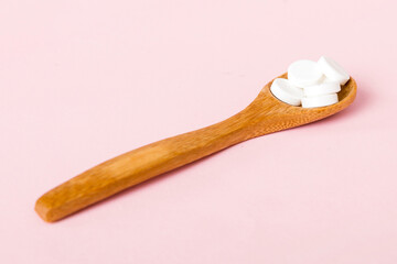 Heap of white pills on colored background. Tablets scattered on a table. Pile of red soft gelatin capsule. Vitamins and dietary supplements concept