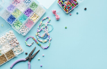 Crafting colorful beaded jewelry on a blue surface with tools and a variety of beads