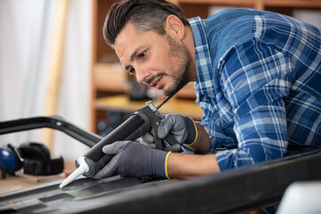 man applying silicone sealant with caulking gun
