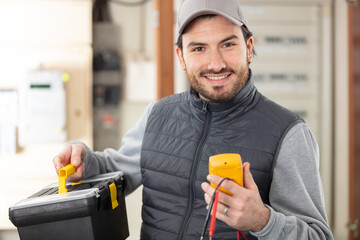 portrait of male electrician holding toolbox and multimeter