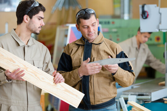 tutor training apprentice carpenter to use woodworking implement