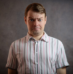 Man in shirt on dark background with surprised face.