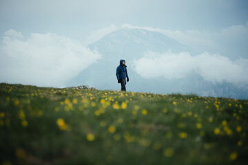 Creative post-apocalyptic portrait with a gas mask in a field with yellow flowers in the mountains