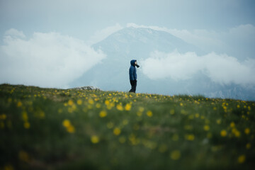 Creative post-apocalyptic portrait with a gas mask in a field with yellow flowers in the mountains