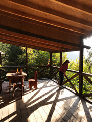 Woman enjoying serene forest view from wooden cabin terrace
