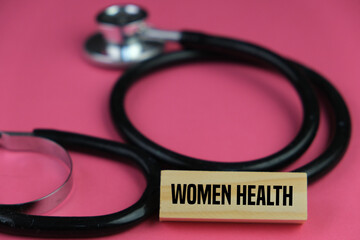 Selective focus image of stethoscope and note with Women Health wording over a pink background. Medical concept