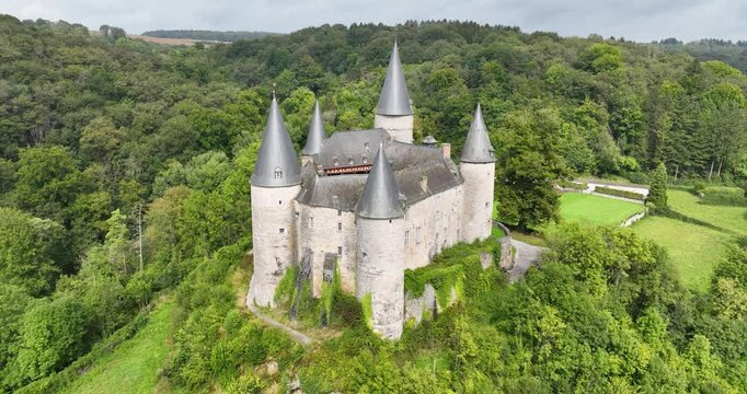 Drone footage of The Castle of Veves surrounded by green lush vegetation