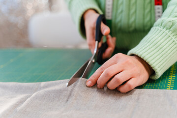 Fashion designer cutting fabric with scissors in studio