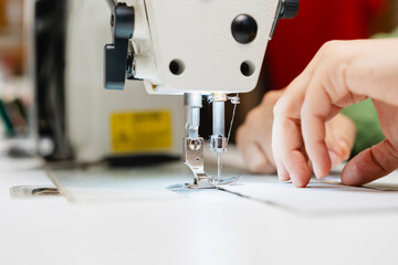 Hands of designer using sewing machine in fashion studio