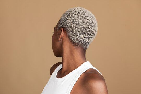 Young woman with short gray hair against beige background