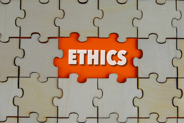 Fototapeta premium Ethics words on the missing part of wooden puzzle with letters, ethics moral philosophy concept, business and management concept. yellow background. 