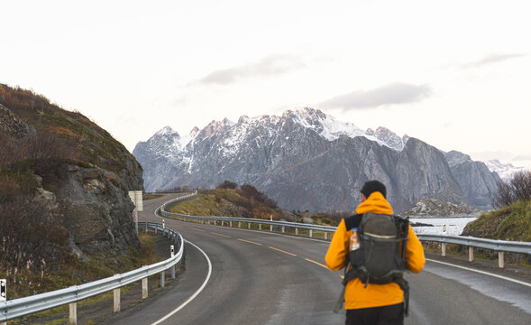 Man with backpack walking on mountain road and exploring at vacation