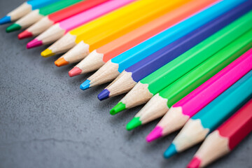 Set of colored pencils lined up on a gray background