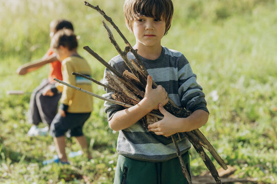 Boy holding wooden sticks on sunny day