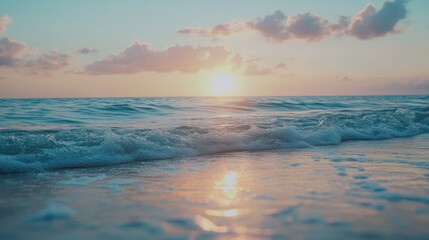 Fototapeta premium Summer sunset over calm ocean waves highlighting vibrant colors in the sky and soft reflections on sandy shores with gentle clouds scattered above.