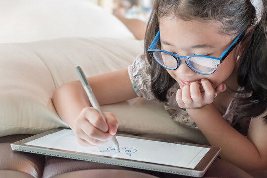 School child girl kid using internet online learning on mobile tablet reading looking at digital screen for educational study for Children’s Eye Health and Safety Month and Blue Light Awareness Day