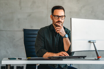 Successful busy professional business man working on computer sitting at desk.