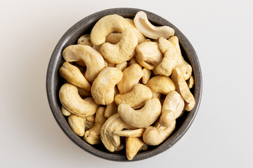 Cashew nuts in grey bowl on white background. 