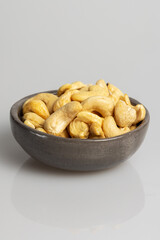 Fototapeta premium Cashew nuts in grey bowl on white background. 