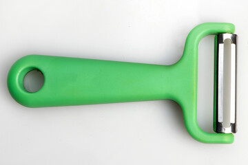 Green vegetable peeler with stainless steel blade isolated on white background. Kitchen utensils and equipment