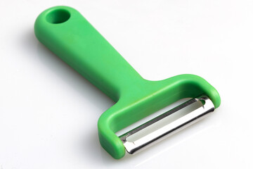 Green vegetable peeler with stainless steel blade isolated on white background. Kitchen utensils and equipment