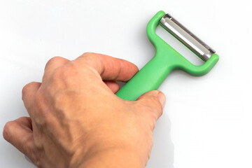 Green vegetable peeler with stainless steel blade isolated on white background. Kitchen utensils and equipment