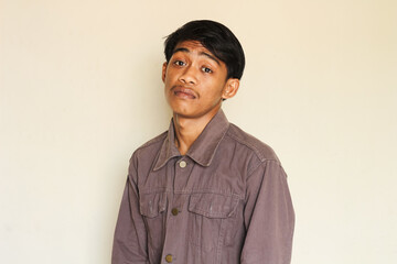 Young Asian man with a limp and tired facial expression isolated on a white background.