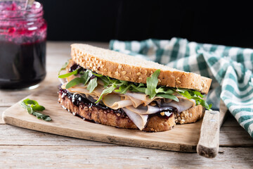 Turkey sandwich with cranberry sauce for Thanksgiving on wooden table