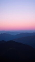Fototapeta premium mountains are silhouetted against a pink sky at sunset