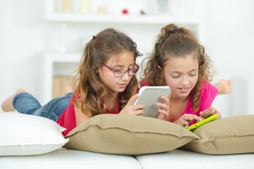 two sisters are using tablet and phone